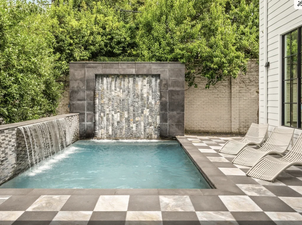The backyard at 3835 Olympia Drive is defined by the in-groud gunite pool with water features. 
